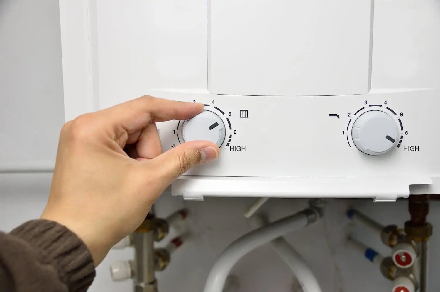 Person adjusting the dial of a tankless water heater to change the settings